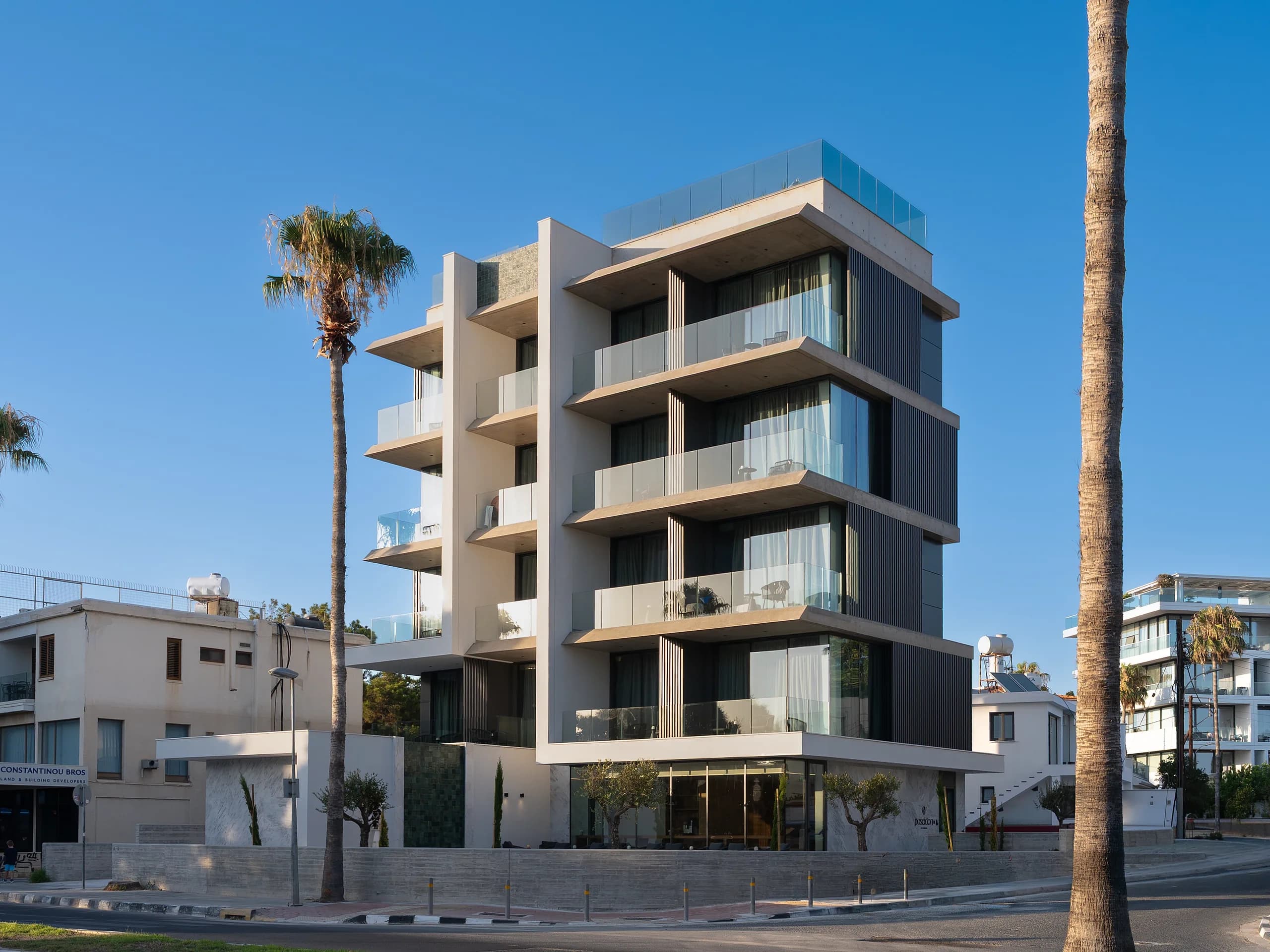 Poseidon building exterior with palm trees and clear blue sky