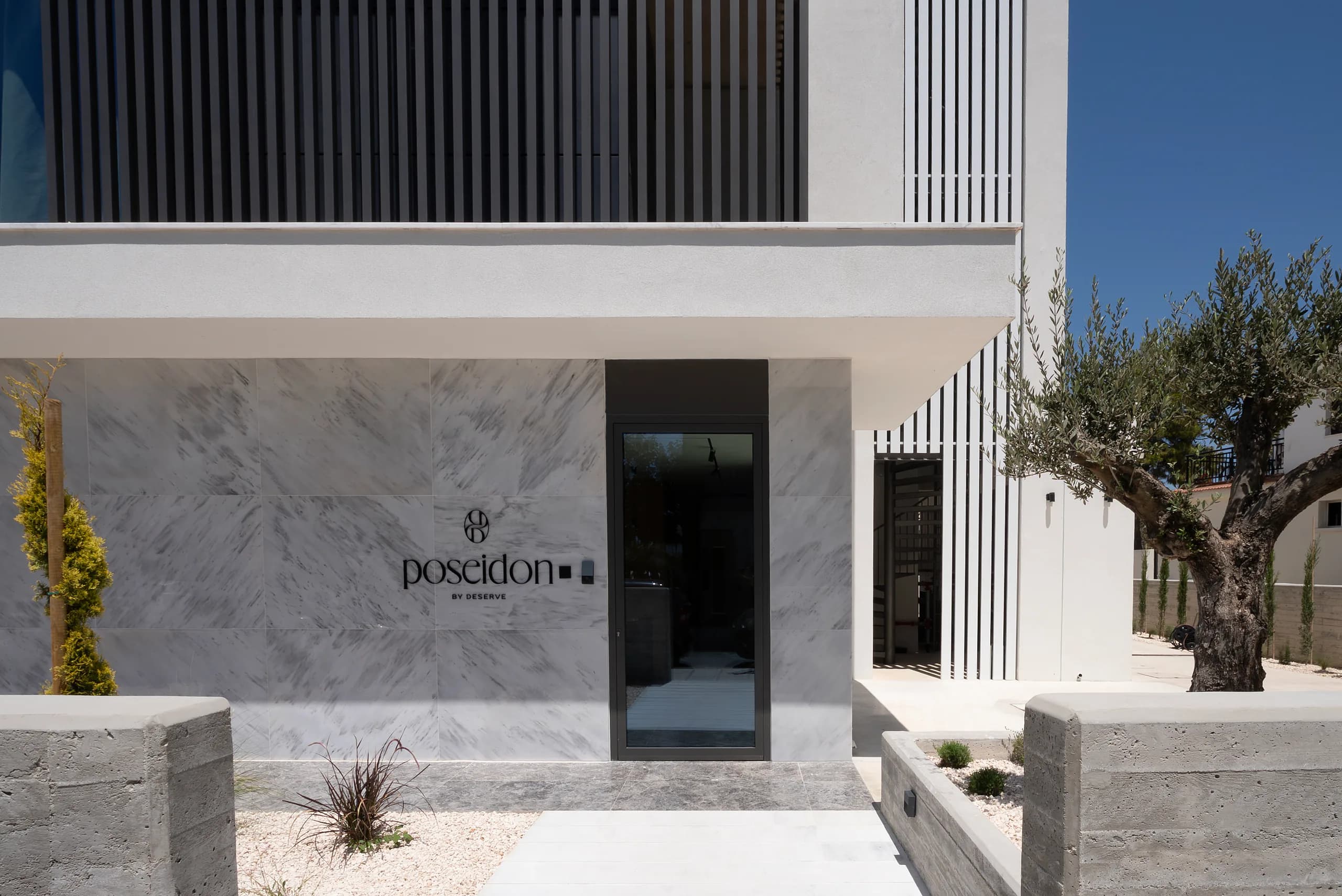 Marble-clad entrance and Poseidon by Deserve signage at street level